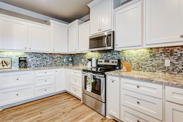 kitchen with decorative backsplash, light hardwood / wood-style flooring, white cabinets, and appliances with stainless steel finishes