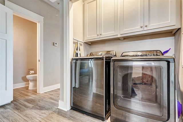 laundry area with cabinets, light wood-type flooring, and washer and clothes dryer