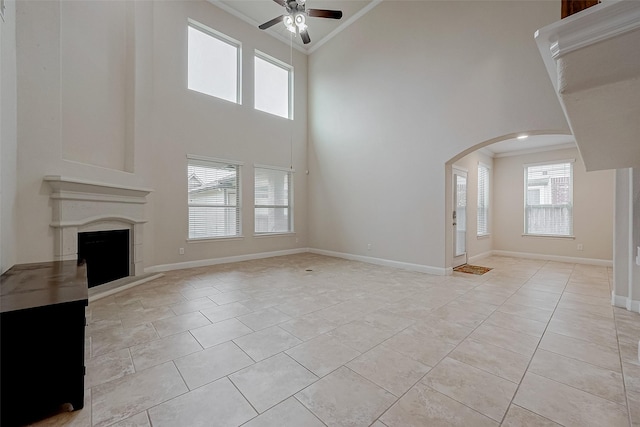 unfurnished living room featuring light tile patterned flooring, a healthy amount of sunlight, ornamental molding, and ceiling fan