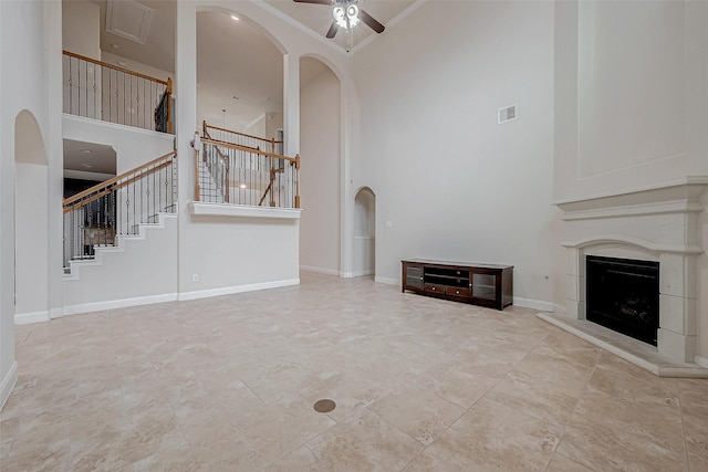 unfurnished living room with ceiling fan, a towering ceiling, and ornamental molding