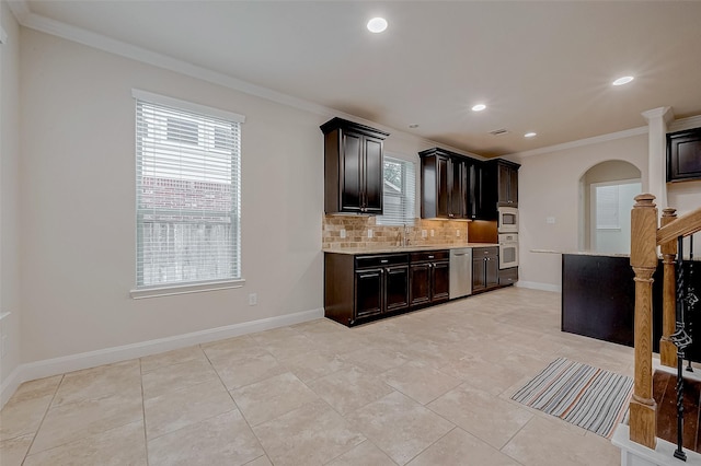 kitchen with stainless steel appliances, ornamental molding, a wealth of natural light, and backsplash