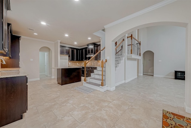 kitchen featuring sink, crown molding, backsplash, dark brown cabinets, and light stone counters