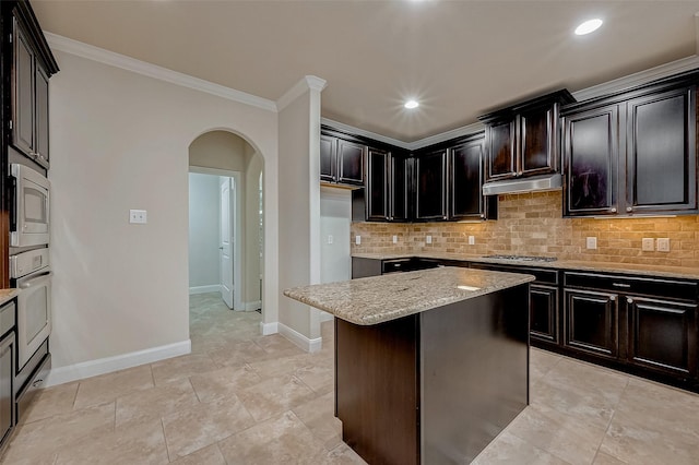 kitchen with light stone counters, a center island, ornamental molding, stainless steel appliances, and backsplash