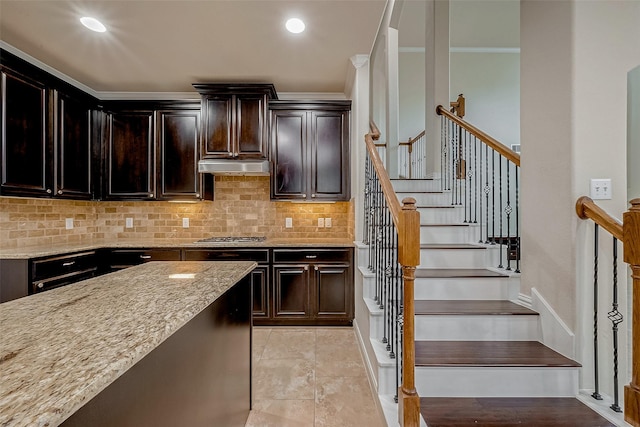 kitchen with dark brown cabinetry, light stone countertops, and backsplash