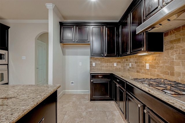 kitchen with crown molding, stainless steel appliances, light stone counters, decorative backsplash, and exhaust hood