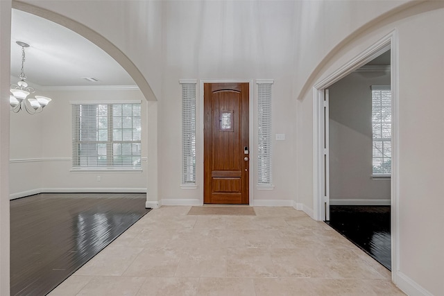 foyer with an inviting chandelier, crown molding, and a healthy amount of sunlight