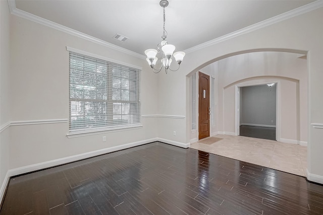 empty room featuring hardwood / wood-style flooring, ornamental molding, and a chandelier