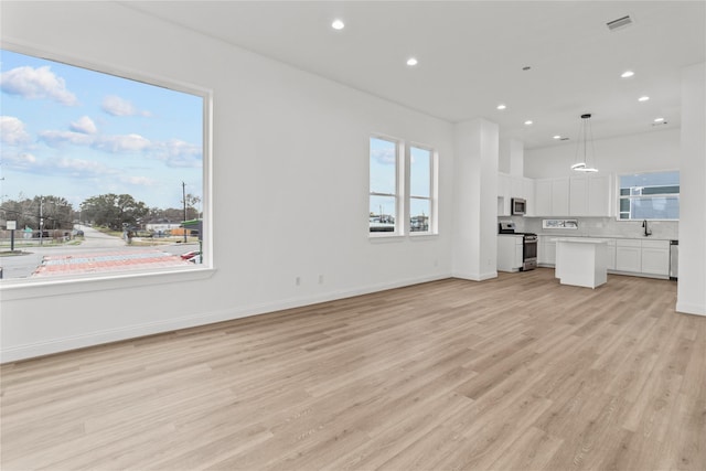 unfurnished living room with sink and light hardwood / wood-style floors