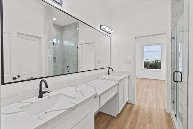 bathroom with wood-type flooring, a shower with shower door, and vanity