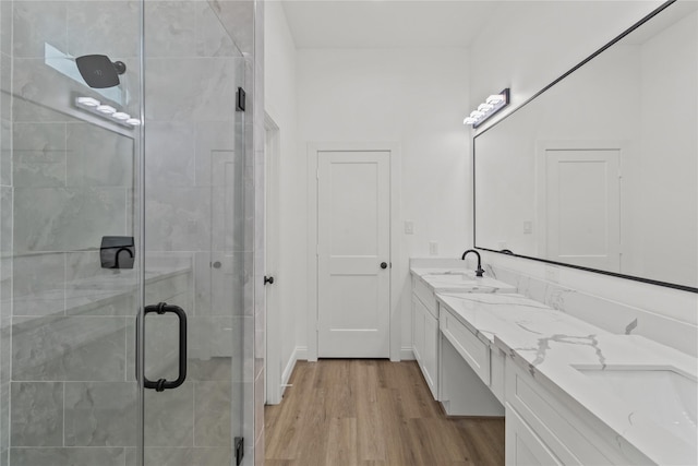 bathroom with wood-type flooring, a shower with shower door, and vanity