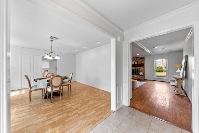 dining space with crown molding, a fireplace, and light hardwood / wood-style flooring