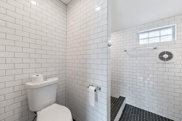 bathroom with toilet, tile walls, and a tile shower