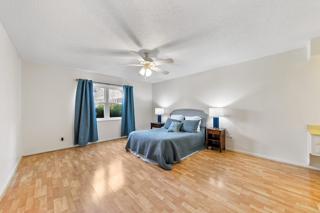 bedroom with ceiling fan, light hardwood / wood-style flooring, and a textured ceiling