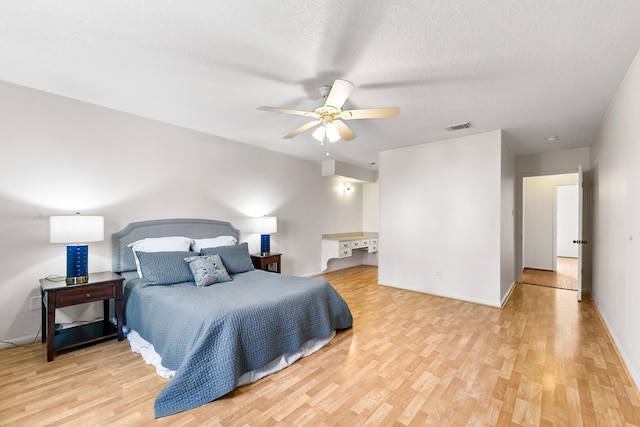 bedroom with ceiling fan, light hardwood / wood-style floors, and a textured ceiling