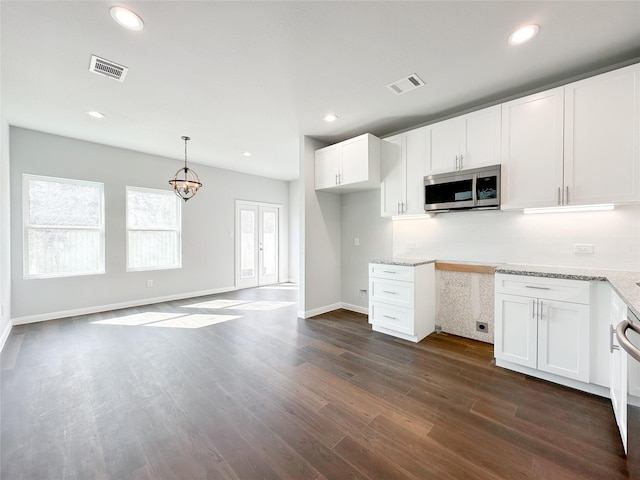 kitchen with decorative light fixtures, light stone countertops, dark hardwood / wood-style floors, and white cabinets