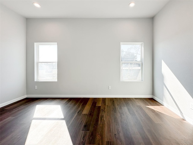 empty room featuring plenty of natural light and dark hardwood / wood-style floors