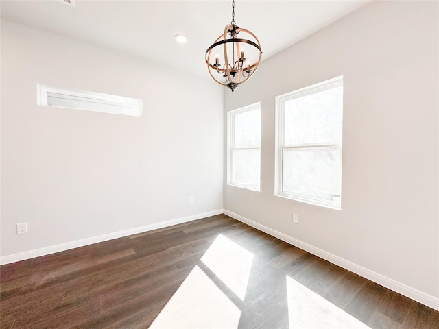 empty room with dark hardwood / wood-style floors and a notable chandelier