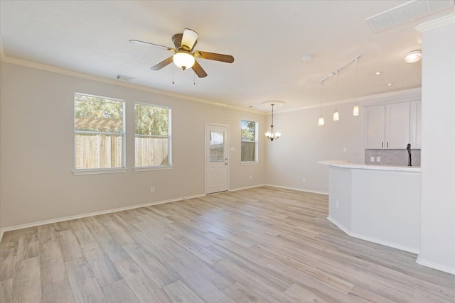 unfurnished living room with crown molding, ceiling fan with notable chandelier, and light hardwood / wood-style floors