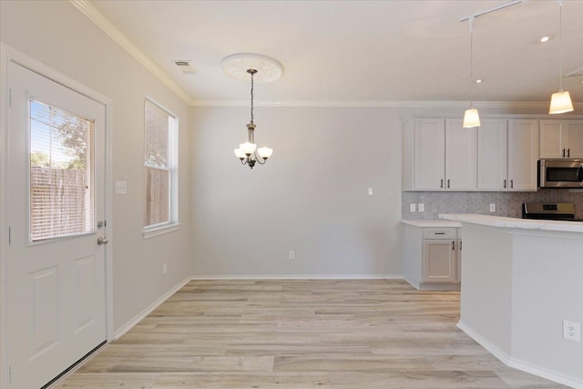 kitchen featuring stainless steel appliances, white cabinetry, ornamental molding, and decorative light fixtures