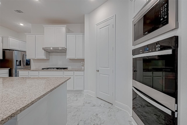 kitchen with white cabinetry, appliances with stainless steel finishes, and light stone counters