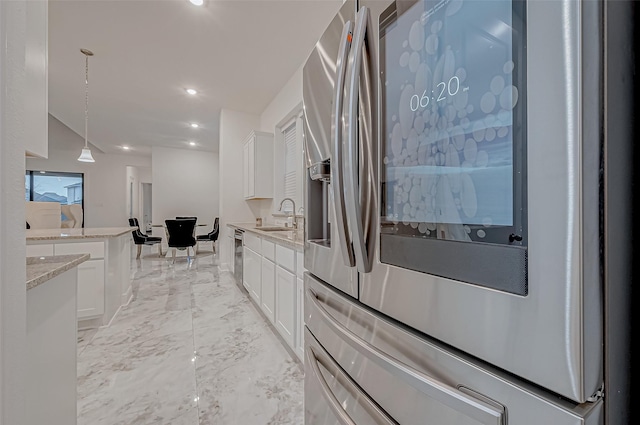 kitchen featuring sink, white cabinetry, stainless steel fridge with ice dispenser, pendant lighting, and light stone countertops