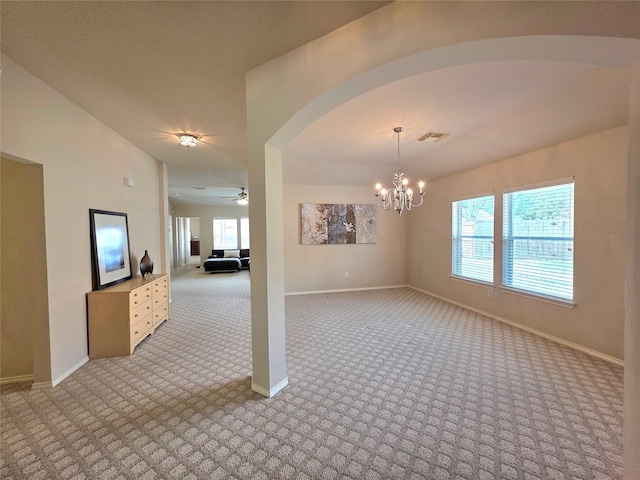 spare room with ceiling fan with notable chandelier and light carpet