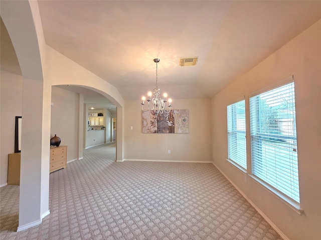 carpeted empty room with a notable chandelier