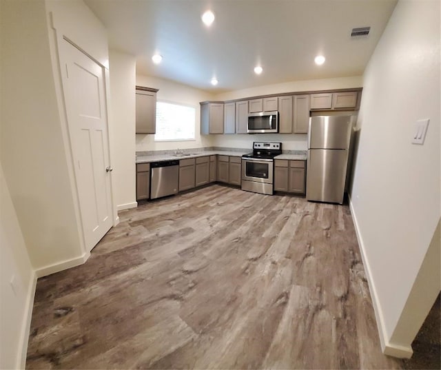 kitchen with appliances with stainless steel finishes, sink, gray cabinetry, and light wood-type flooring