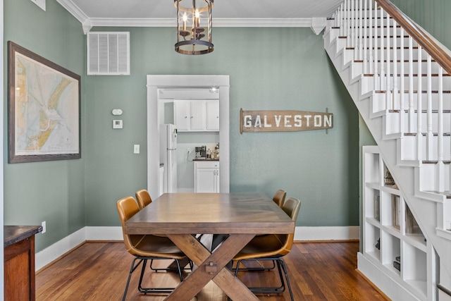 dining area featuring ornamental molding, a notable chandelier, and dark hardwood / wood-style flooring