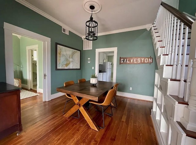 dining area featuring an inviting chandelier, ornamental molding, and dark hardwood / wood-style floors