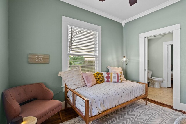 tiled bedroom with ceiling fan, ornamental molding, and connected bathroom