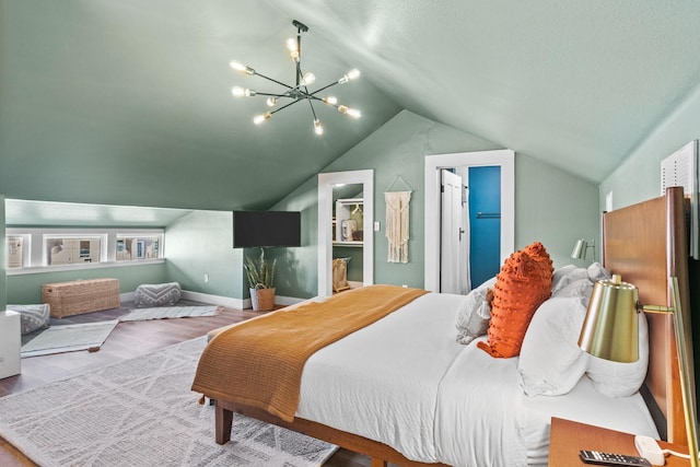 bedroom featuring lofted ceiling, a notable chandelier, wood-type flooring, a spacious closet, and a closet