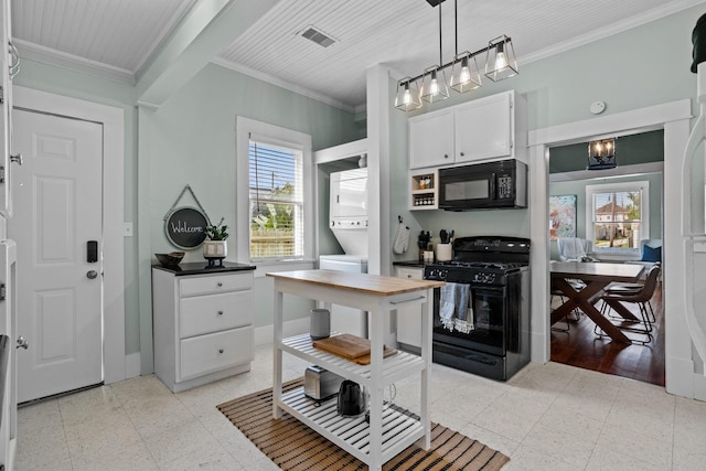 kitchen with decorative light fixtures, white cabinets, stacked washer and clothes dryer, black appliances, and crown molding