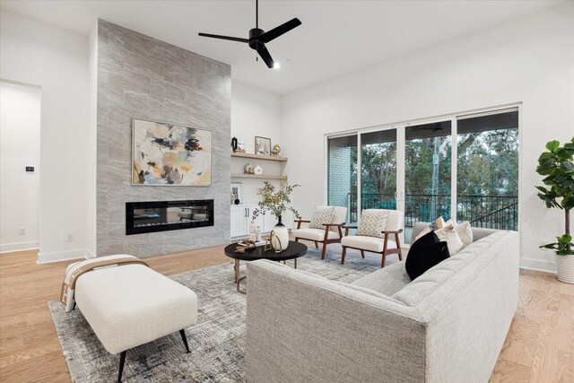 living room featuring a tiled fireplace, hardwood / wood-style floors, and ceiling fan