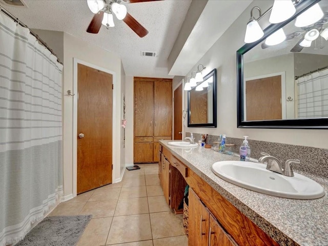 bathroom with ceiling fan, vanity, tile patterned flooring, and a textured ceiling