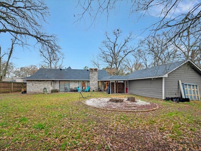 rear view of property featuring a fire pit and a lawn