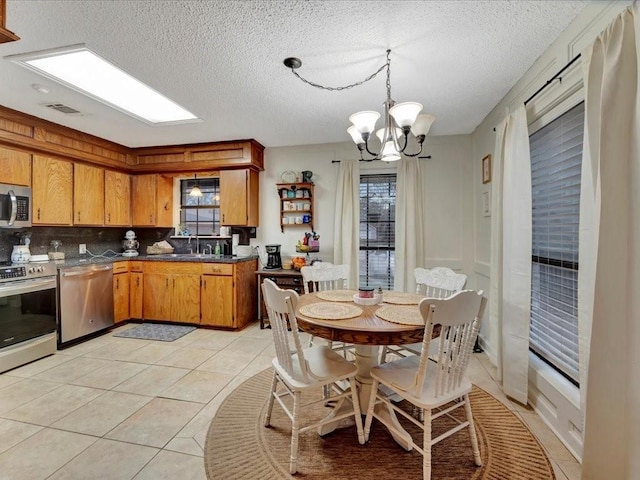 4 Rain Drop Dr, Lufkin, TX 75901 - kitchen with stainless steel appliances, dark countertops, a sink, light tile patterned flooring, and a chandelier