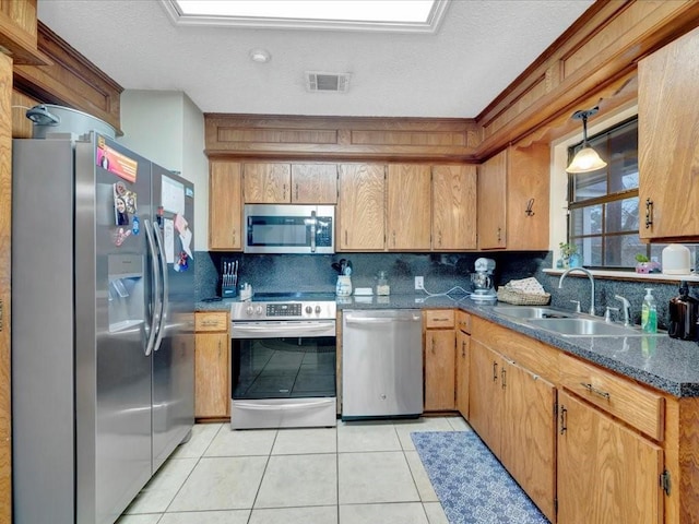 kitchen with tasteful backsplash, appliances with stainless steel finishes, sink, and light tile patterned floors