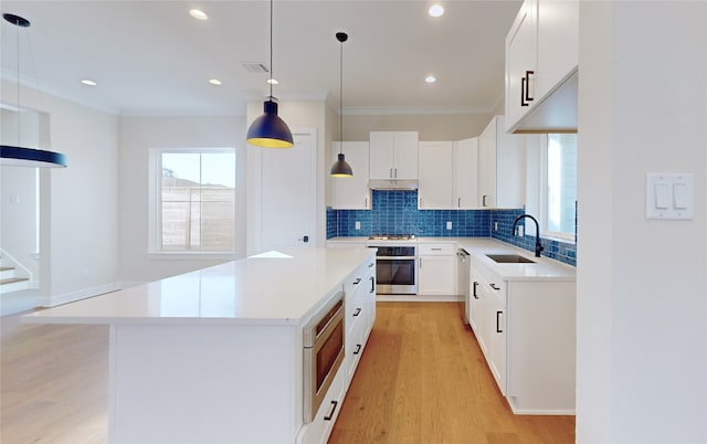 kitchen featuring sink, a center island, appliances with stainless steel finishes, pendant lighting, and white cabinets