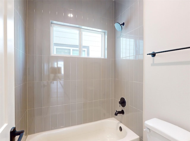 bathroom with tiled shower / bath combo and toilet