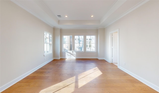 unfurnished room featuring crown molding, a tray ceiling, and light wood-type flooring