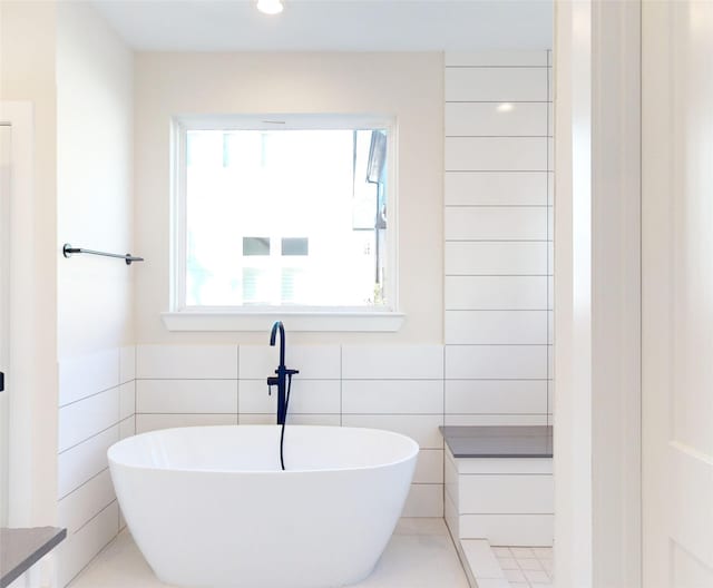 bathroom featuring tile walls and a bath