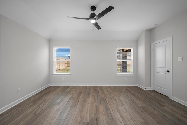 spare room featuring ceiling fan, lofted ceiling, a wealth of natural light, and dark hardwood / wood-style flooring