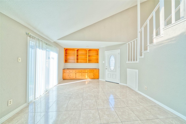 tiled entrance foyer featuring lofted ceiling and a textured ceiling