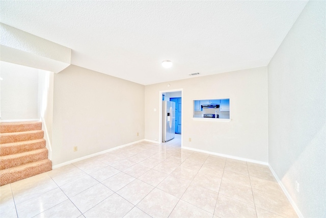 unfurnished room with light tile patterned floors and a textured ceiling