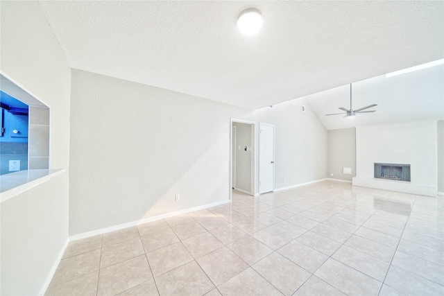 unfurnished living room featuring a brick fireplace, a textured ceiling, lofted ceiling, and ceiling fan