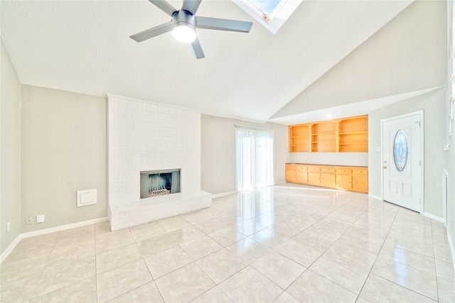 unfurnished living room with a brick fireplace, light tile patterned floors, ceiling fan, and a skylight