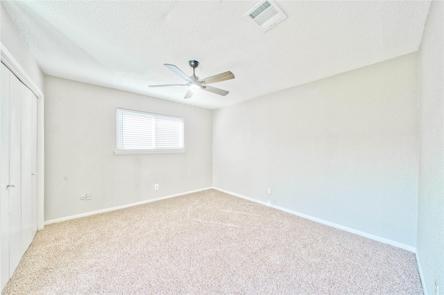 carpeted spare room featuring ceiling fan and a textured ceiling