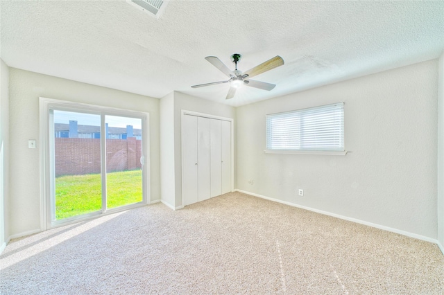 unfurnished bedroom with ceiling fan, light colored carpet, a closet, and a textured ceiling