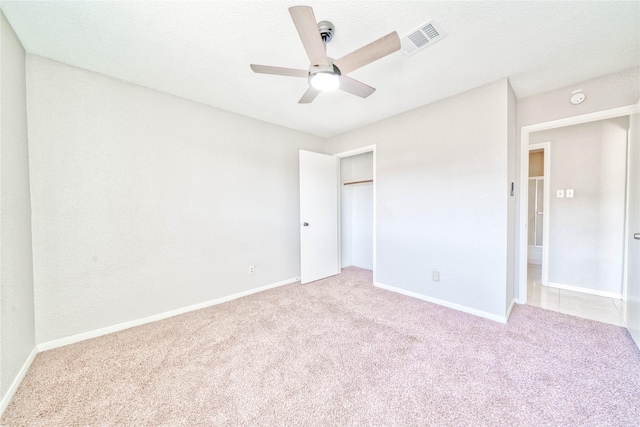 unfurnished bedroom with light carpet, ceiling fan, a closet, and a textured ceiling